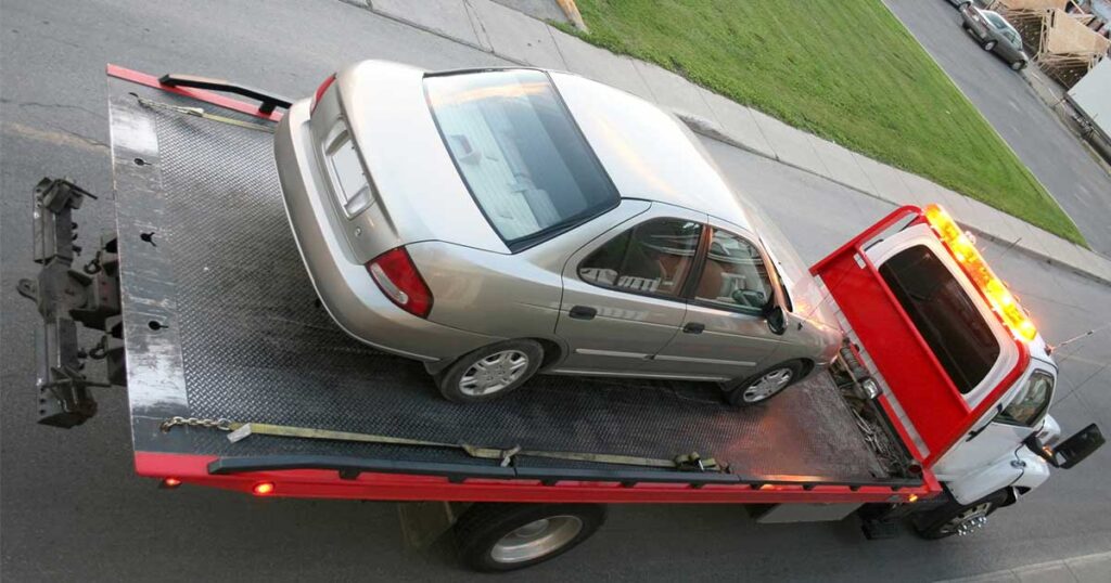 Car being removed on back of tow truck after being bought for cash.