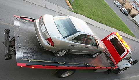 Car being removed on back of tow truck on the road.