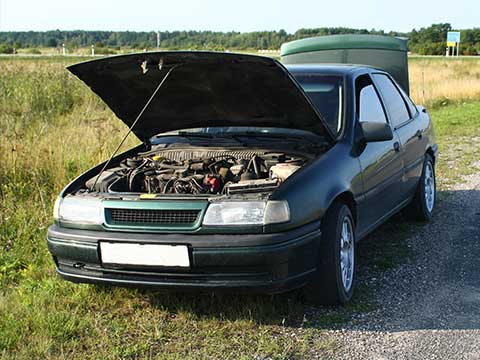 Old car with bonnet and boot open left as junk on side of road