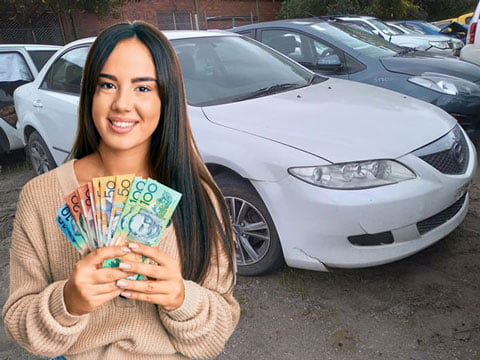 Woman holding up loads of cash she received for scrapping her car with us