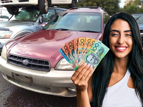 Woman holding up cash she received after selling her Subaru to us.