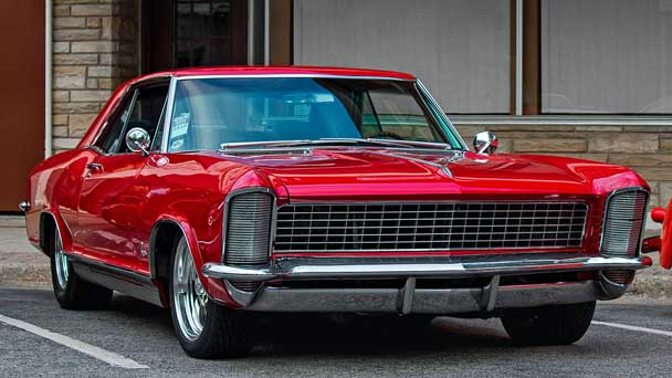 A red rare classic vehicle on a road.