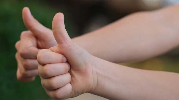 Two different hands showing thumbsup.